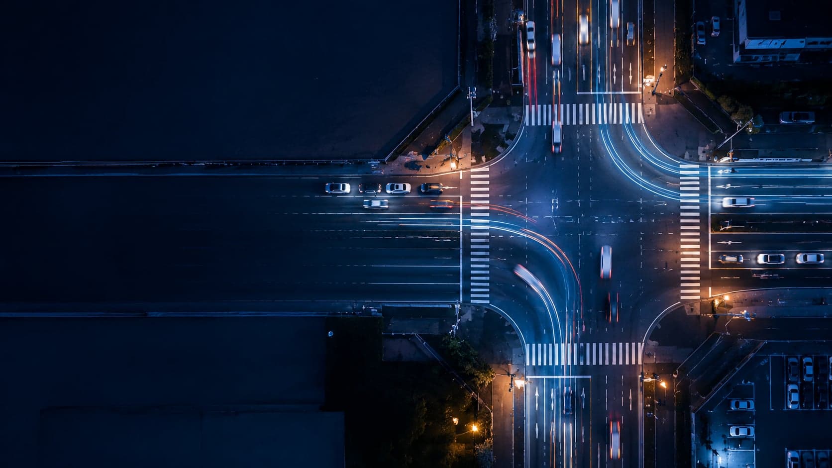 夜の交差点を真上から捉えた写真。行き交う車の光跡が幾筋もの経路を描いている